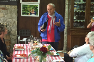 local Italian man holding a bottle of wine and presenting it to a table